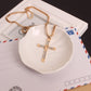 Gold rhinestone cross pendant necklace with chain and pendant on a tray