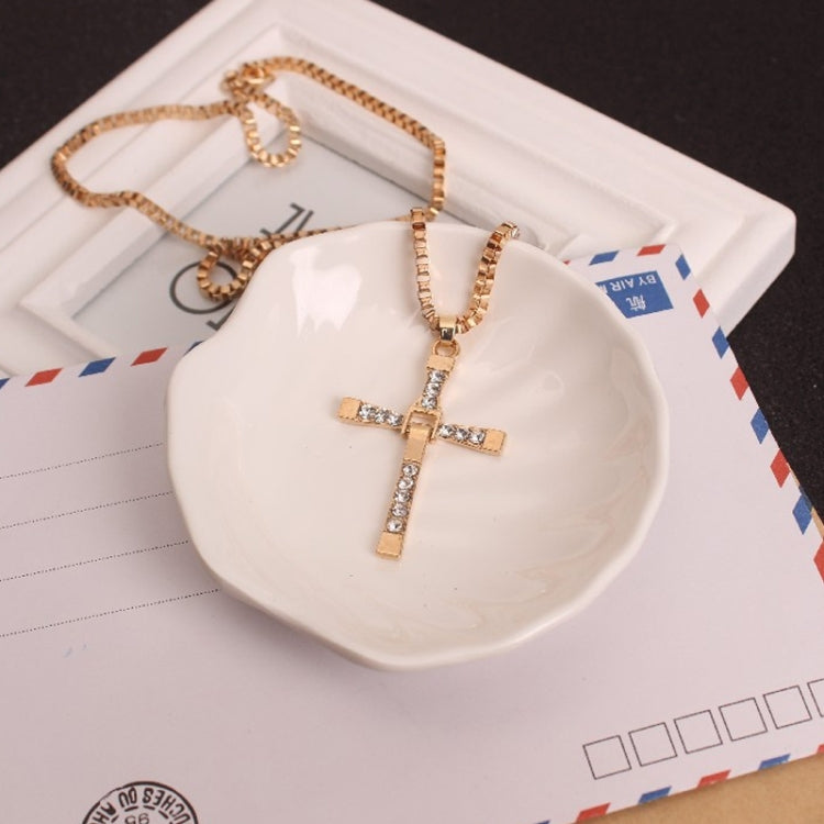 Gold rhinestone cross pendant necklace with chain and pendant on a tray