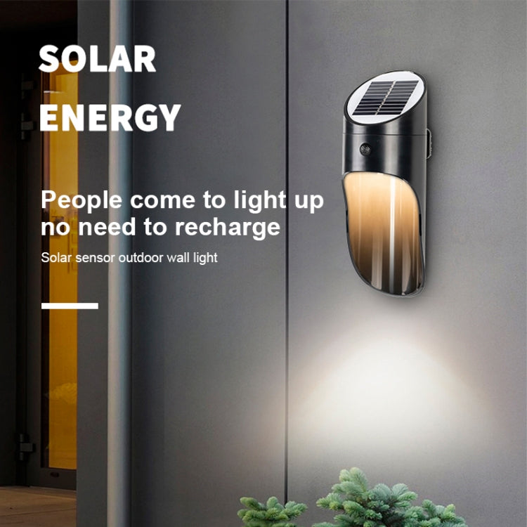 Solar LED wall light with solar panel top, black body emitting warm light