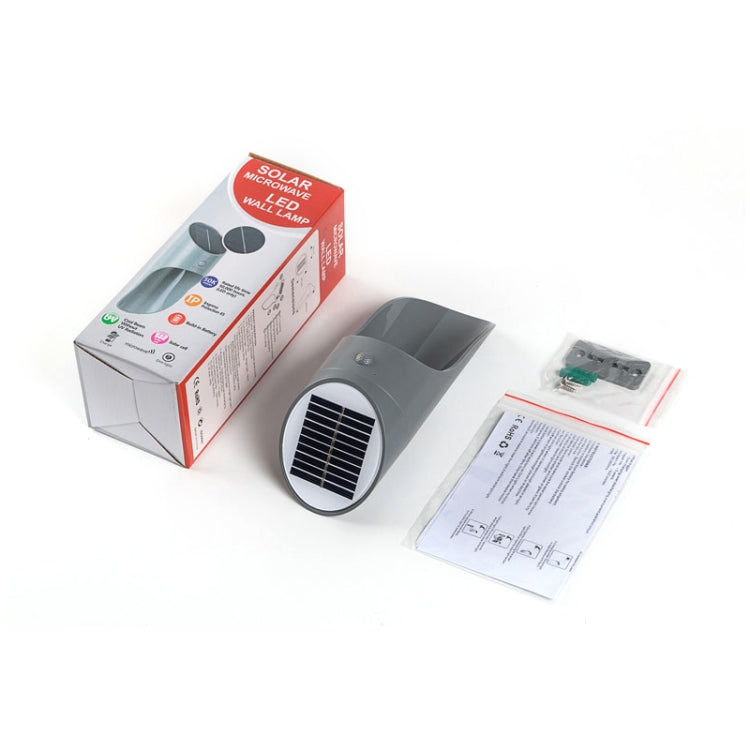 Gray solar LED wall light with round solar panel, shown with retail box and papers
