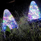 Solar conical garden lamps glowing multicolor through clear cone shades in grass