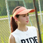Peach pink visor cap with curved brim and smooth, textured lightweight fabric.