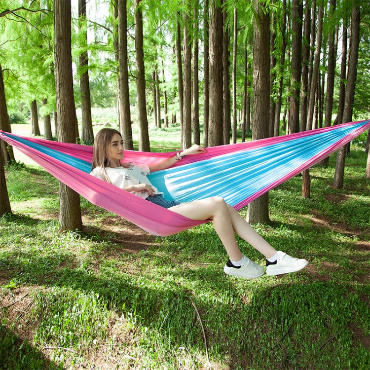 Pink and blue parachute hammock sling with one person relaxing outdoors