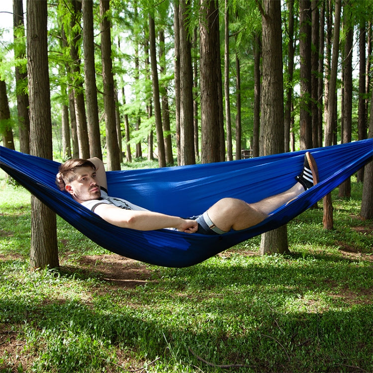 Dark blue parachute hammock swing with one person relaxing outdoors