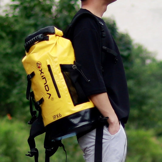 Waterproof 20L dry bag backpack in yellow with black shoulder straps, worn outdoors