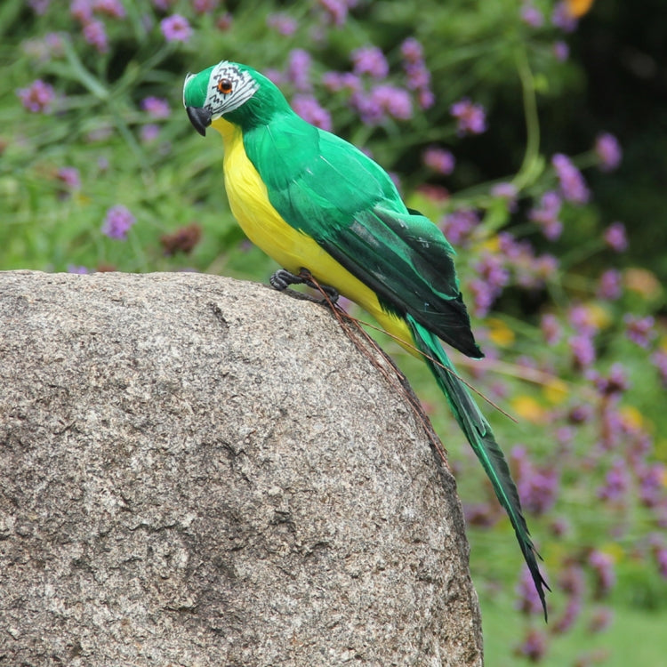 Green simulated parrot ornament perched on a gray stone, long tail visible