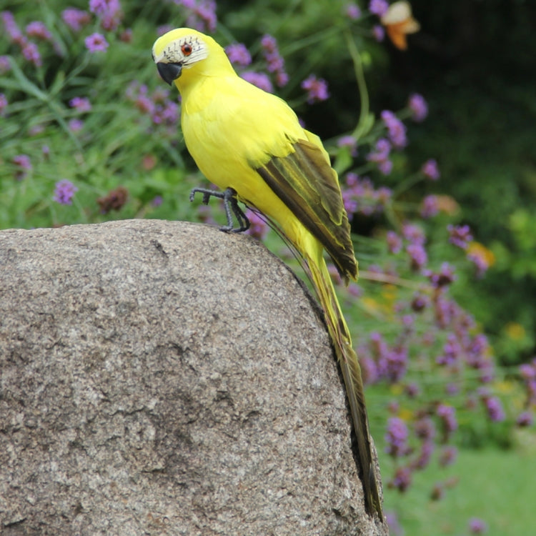 Yellow simulated parrot ornament perched on a gray stone