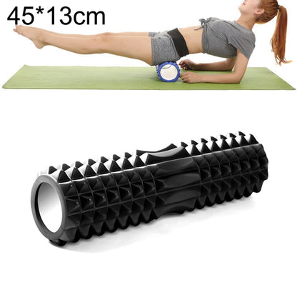 Black EVA yoga muscle massage roller, used under legs on a mat