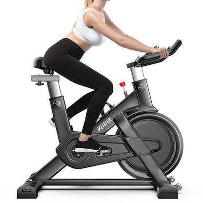 Indoor spinning bicycle with seated rider, black frame and handlebars