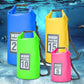 Set of waterproof dry bags in blue, green, yellow, and pink with shoulder straps