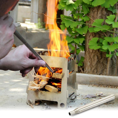 Stainless steel retractable blow torch held beside open campfire