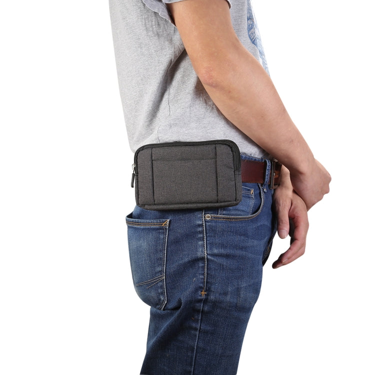Dark gray waist phone bag worn at hip over blue jeans with zippered front