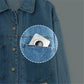 White thermal photo printer tucked in a blue denim jacket pocket