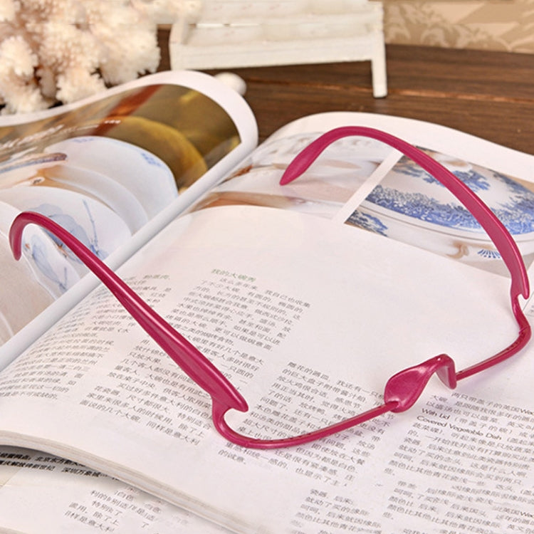 Double eyelid trainer glasses with pink frame resting on open book
