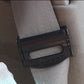 Black car seat belt adjuster clip attached to seat belt webbing, close-up