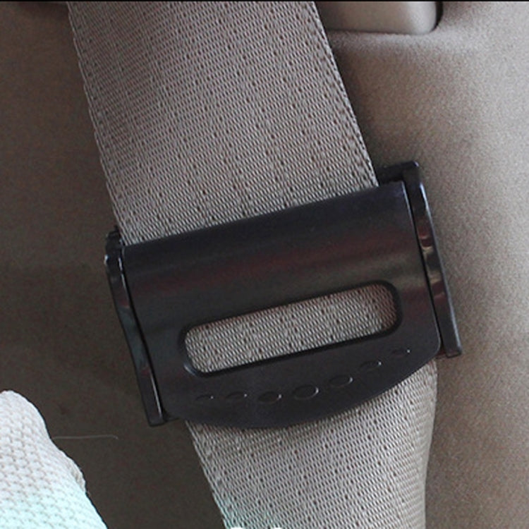 Black car seat belt adjuster clip attached to seat belt webbing, close-up