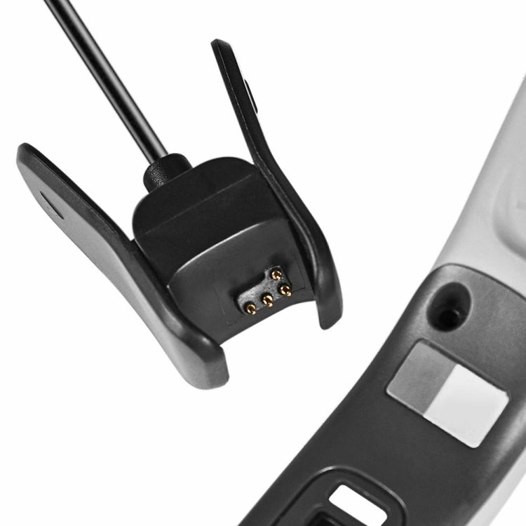 Close-up of black charging clip with exposed connector pins on metal base