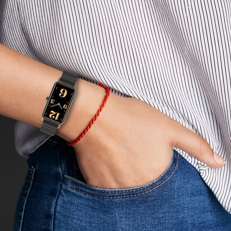 Black metal bead watch strap on wrist with a rectangular fitness smartwatch