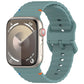 Pine green silicone watch band with wavy ridges, shown attached to a smartwatch