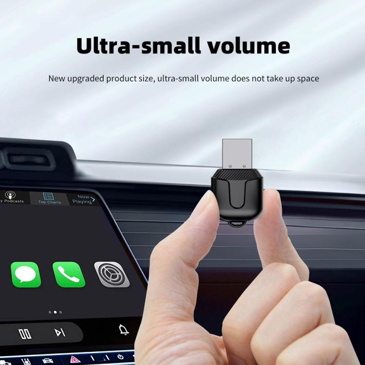 Compact black USB wireless car adapter held near dashboard for CarPlay/Android Auto