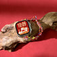 Multicolor braided Apple Watch band with gold charms, wrapped around a watch