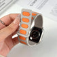 Light gray silicone watch band with orange insets, folded to show its magnetic closure.