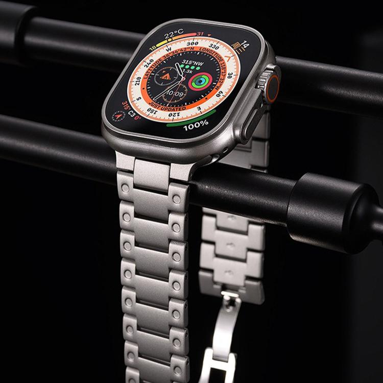Silver metal watch band with broad links and butterfly clasp, attached to an Apple Watch