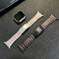 Silver and black stainless steel watch bands with red accents beside a watch