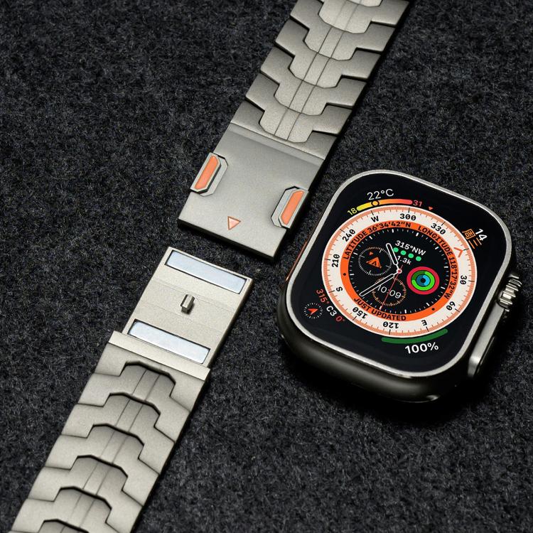 Titanium metal watch band beside a smartwatch, showing the clasp and linked sections.