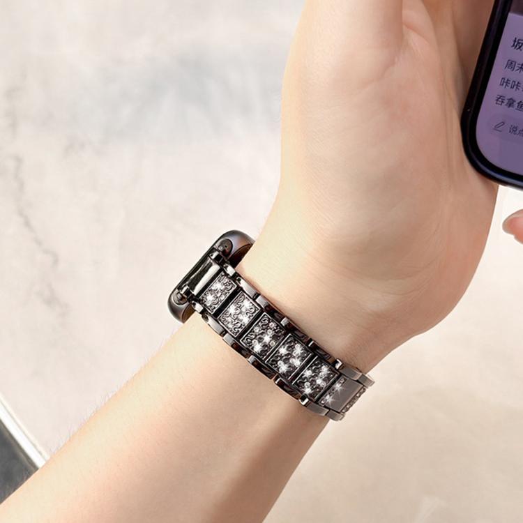 Dark metal watch band with sparkling decorative links, worn on a wrist