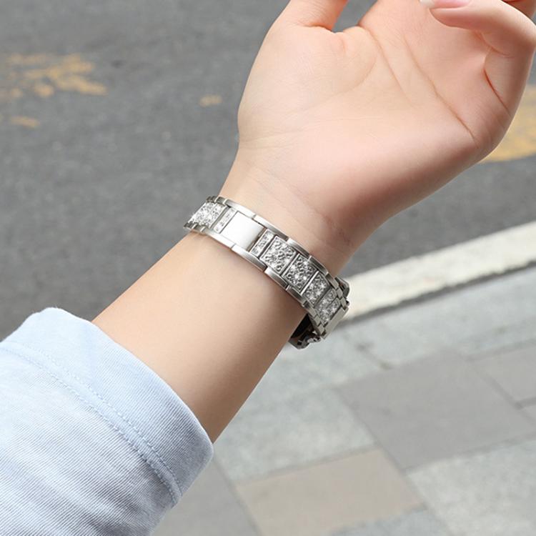 Silver metal watch band with jeweled links, worn on a wrist