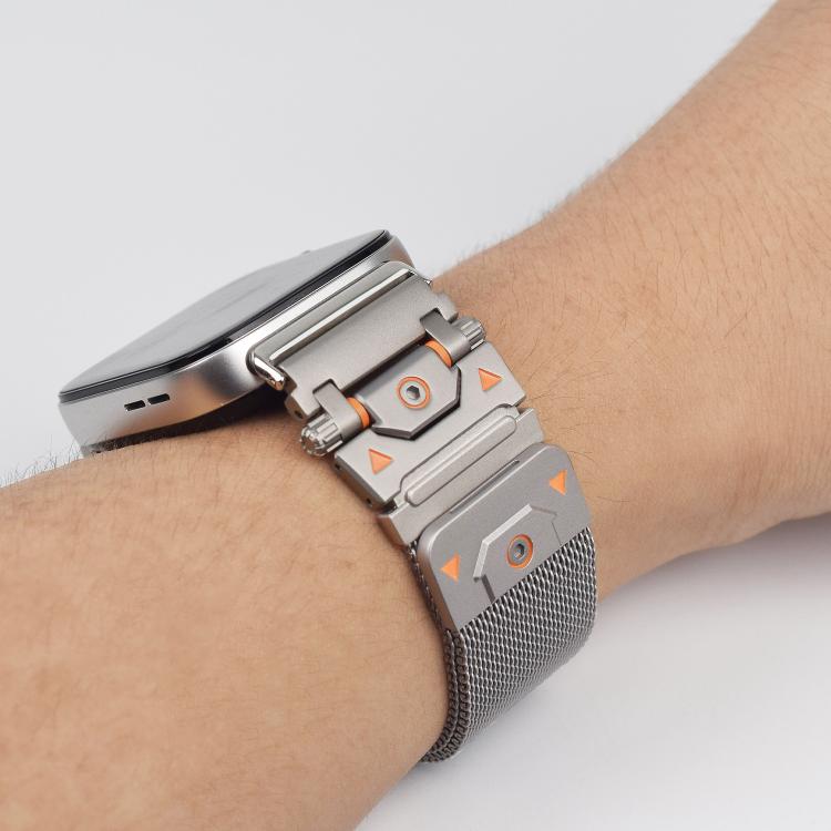Silver Milanese watch band with orange-accented connector worn on a wrist
