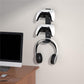 Wall-mounted stand holding two controllers and a headphone set with curved support