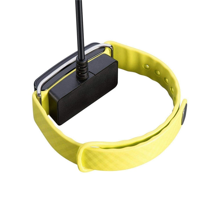 Magnetic charging dock on a yellow watch band with power cable plugged in