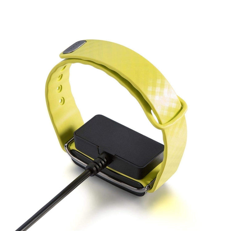 Magnetic charging dock attached to a yellow smartwatch band with cable attached