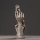 Abstract light-gray sculpted hands with a raised flower, standing decorative figurine.