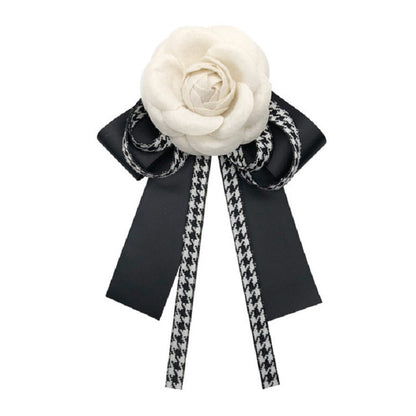 White fabric rose bow brooch with black ribbons and houndstooth tails