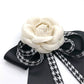 Close-up rose bow brooch with black looped ribbons and houndstooth stripe ties