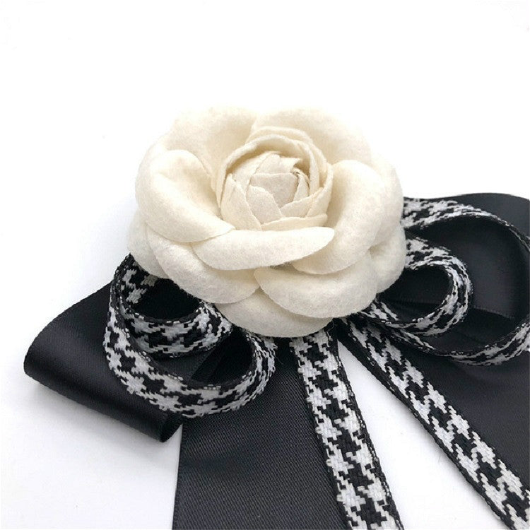 Close-up rose bow brooch with black looped ribbons and houndstooth stripe ties