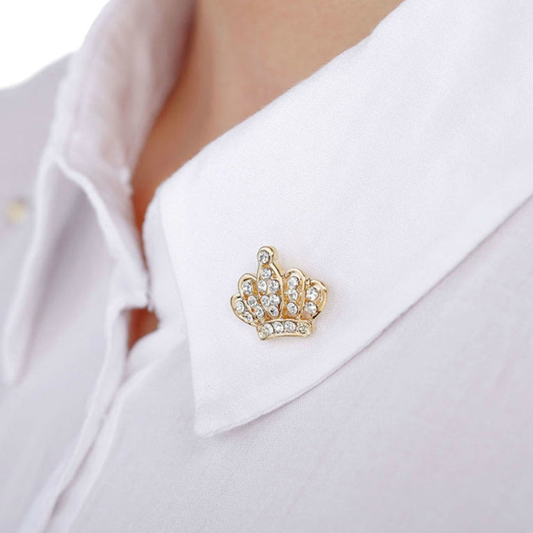 Gold crown-shaped brooch with rhinestone detailing on a white shirt collar