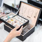 Black double-layer jewelry storage box open with cushioned compartments for necklaces and rings