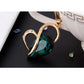 Gold-tone heart crystal pendant with green faceted stone, close-up