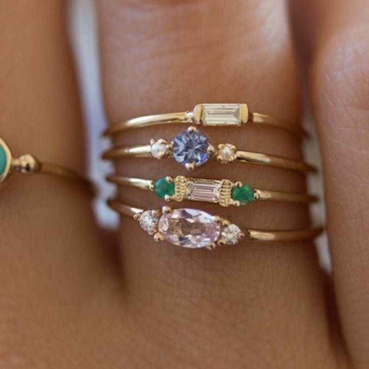 Gold-tone stacked ring with round blue center stone, green baguette accents, and pave bands