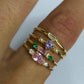 Gold-tone hand rings with purple, green, and clear stones in stacked vintage style