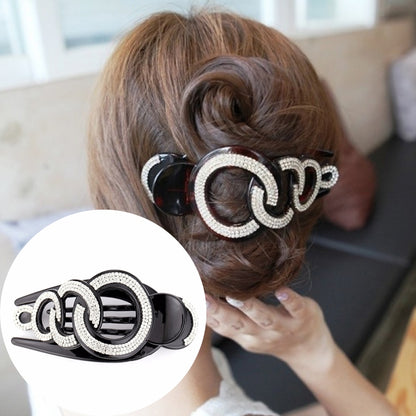 Black rhinestone hair claw clip with large linked oval sparkle detail, clipped in hair.