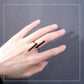 Black geometric open finger ring on hand with two bar accents and open band