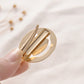 Metal snap hair clip with spring teeth, round gold frame in hand