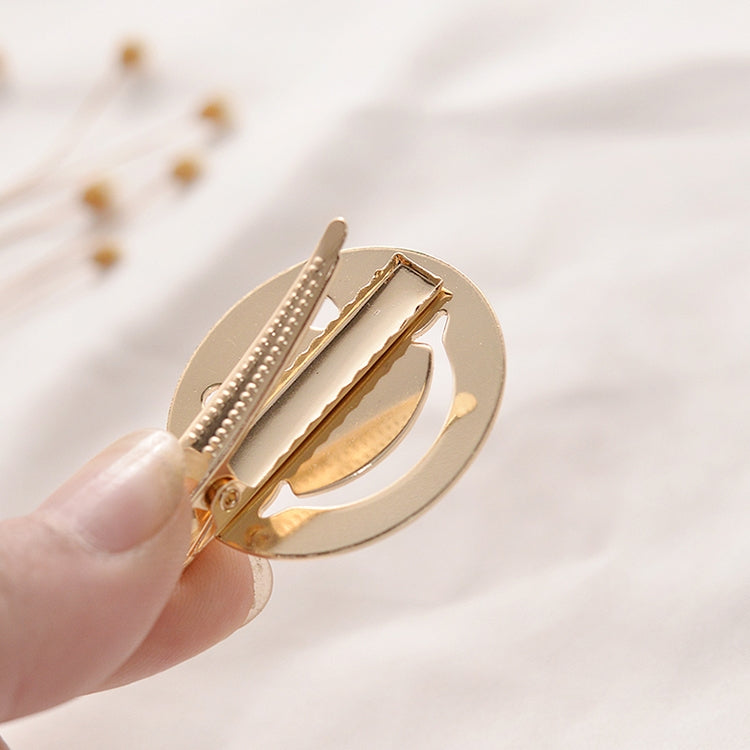 Metal snap hair clip with spring teeth, round gold frame in hand