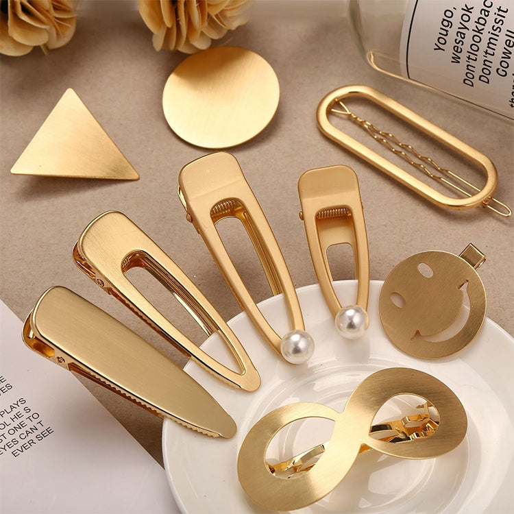 Assorted gold metal snap hair clips with decorative shapes and pearl accents