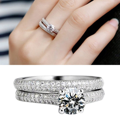 Silver double-row wedding ring with raised center zircon solitaire on a woman’s hand